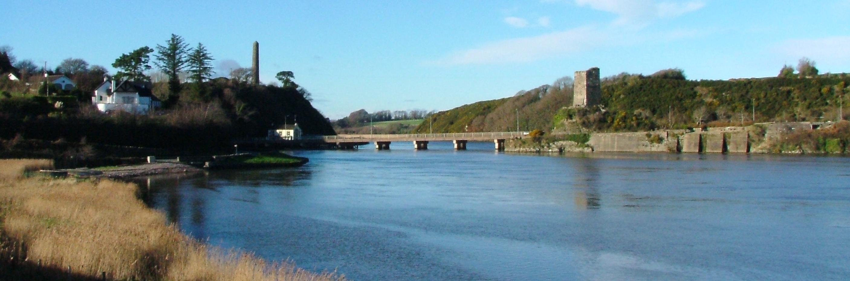 A river with a bridge going across it and the ruins of a castle on one side of the river