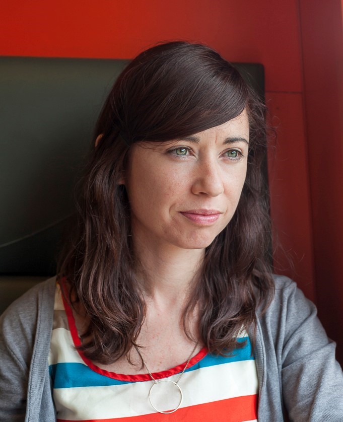 Image of artist Eleanor Duffin looking away from the camera, with brown hair straight hair and fringe, a stripy top, cardigan and necklace on.