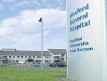 Sign outside Wexford General Hospital saying Wexford General Hospital with a sunny blue sky background and green grass